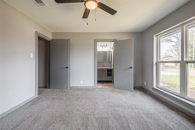 unfurnished bedroom with carpet floors, multiple windows, a sink, and visible vents