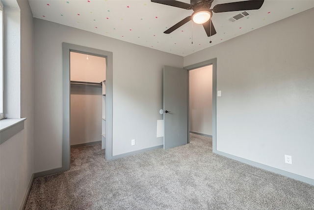 unfurnished bedroom with a closet, visible vents, a spacious closet, carpet flooring, and baseboards