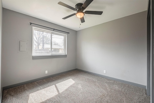 carpeted empty room featuring electric panel, a ceiling fan, and baseboards