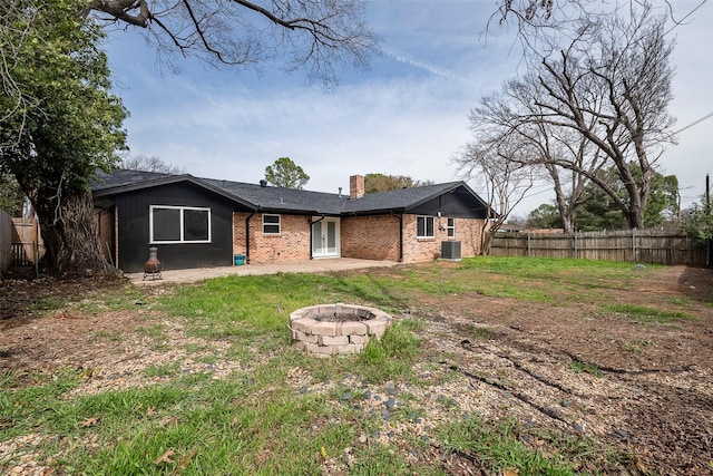 back of property with brick siding, a patio, a chimney, fence, and a fire pit