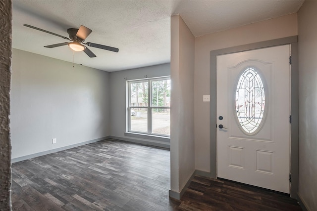 entrance foyer with dark wood-type flooring, a textured ceiling, baseboards, and a ceiling fan