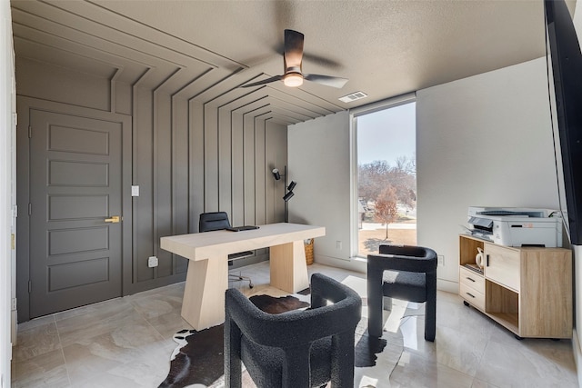 office area with ceiling fan, expansive windows, visible vents, and a textured ceiling