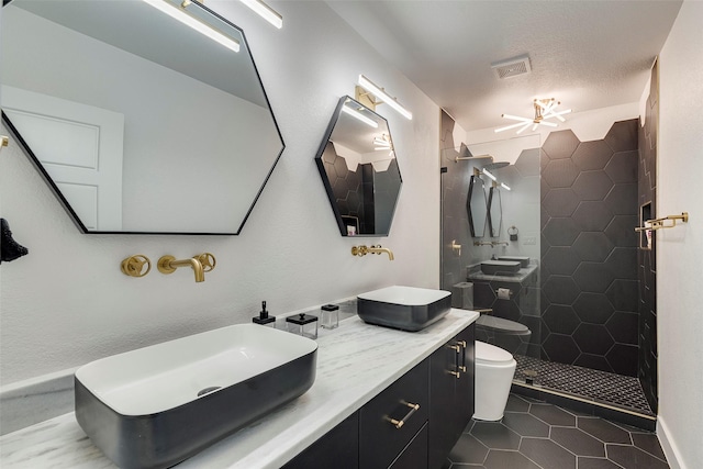 bathroom with visible vents, toilet, a tile shower, a sink, and tile patterned floors