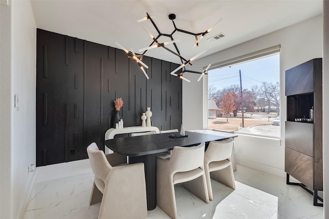 dining room featuring marble finish floor, visible vents, wood walls, and baseboards