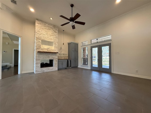 unfurnished living room with ornamental molding, french doors, a stone fireplace, and visible vents