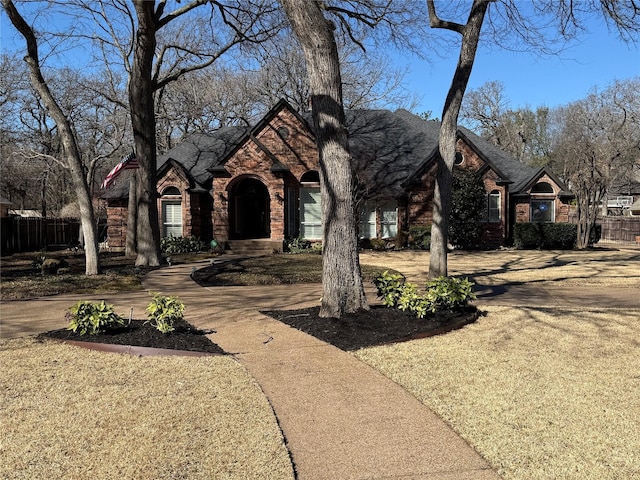 view of front of property featuring stone siding, brick siding, and fence