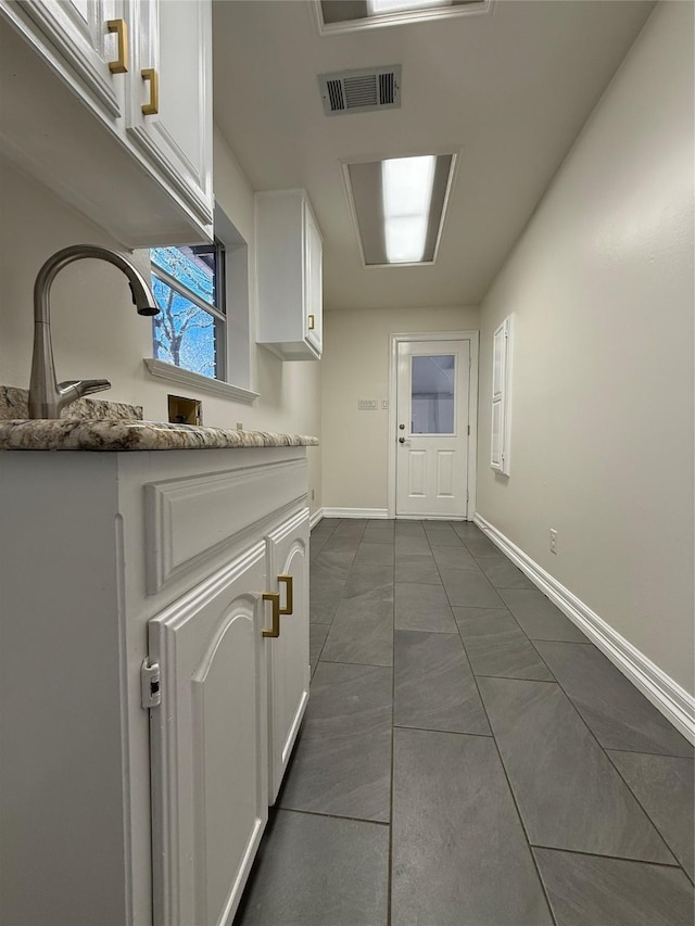 interior space featuring visible vents, cabinet space, a sink, and baseboards