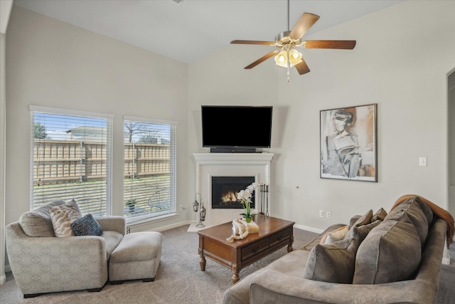 living area featuring carpet floors, lofted ceiling, ceiling fan, a lit fireplace, and baseboards