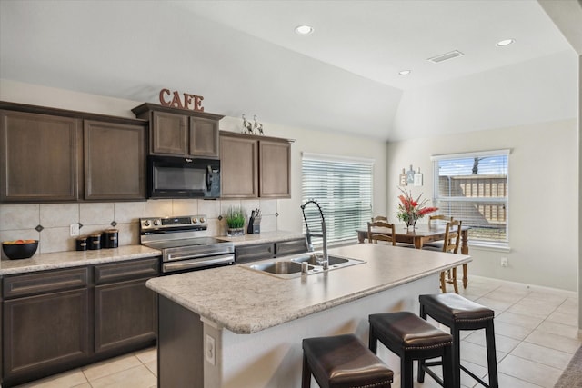 kitchen featuring black microwave, lofted ceiling, a sink, stainless steel electric range, and tasteful backsplash