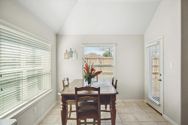 dining area featuring baseboards, vaulted ceiling, and light tile patterned flooring