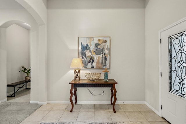 tiled foyer with baseboards and arched walkways