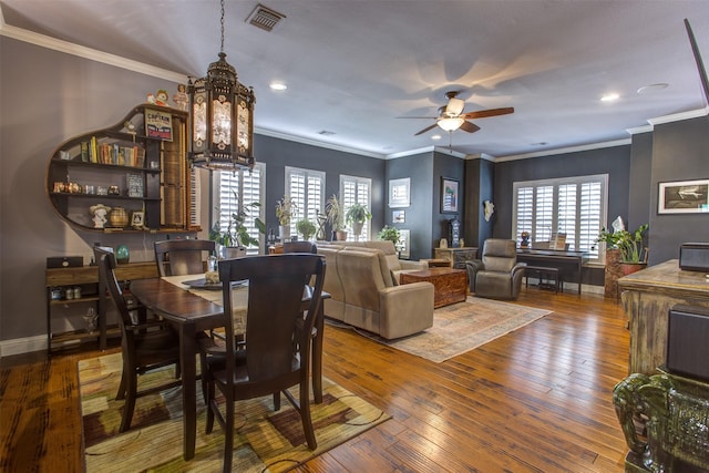 dining room featuring ornamental molding, hardwood / wood-style flooring, visible vents, and baseboards