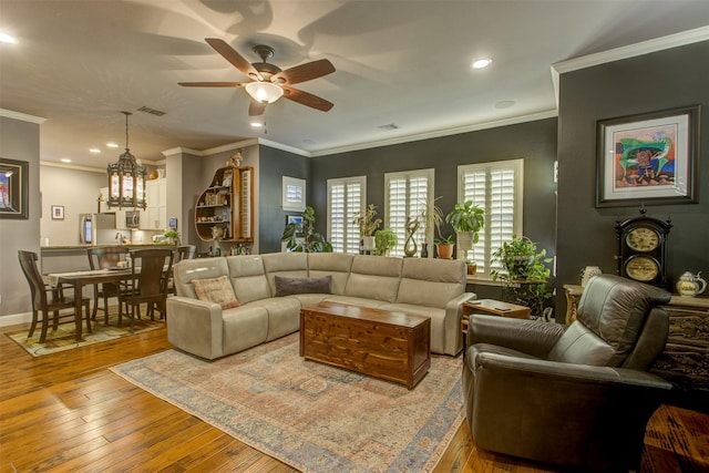 living area featuring visible vents, ornamental molding, ceiling fan, baseboards, and hardwood / wood-style flooring