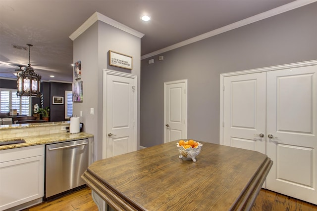 kitchen with light stone counters, light wood-style floors, white cabinets, ornamental molding, and stainless steel dishwasher