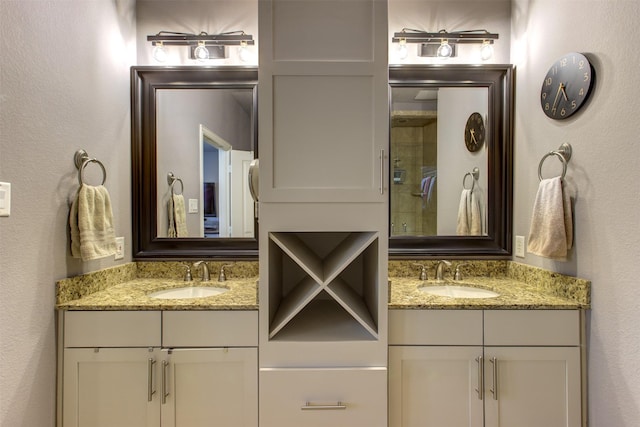 bathroom featuring a textured wall, two vanities, and a sink