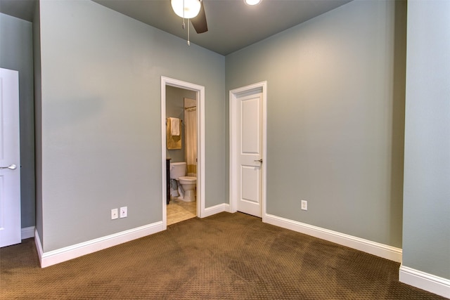 unfurnished bedroom with baseboards, dark carpet, and connected bathroom