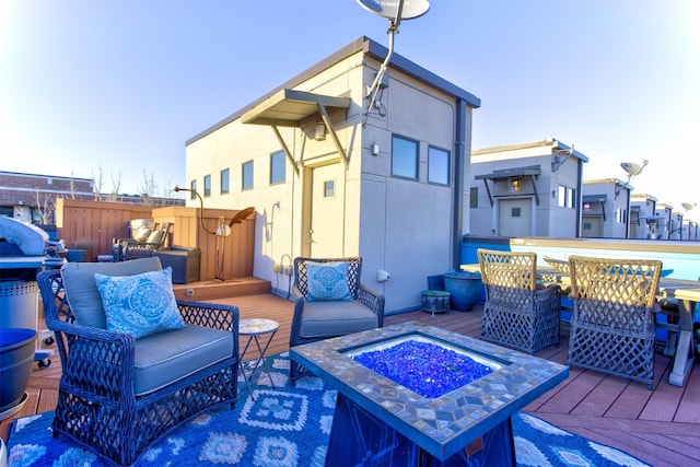 rear view of house featuring stucco siding, an outdoor living space with a fire pit, and a wooden deck