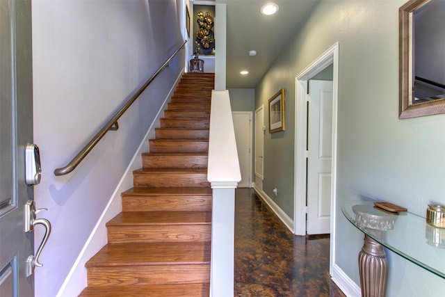 stairway featuring finished concrete flooring, baseboards, and recessed lighting