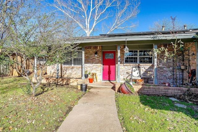 view of front of house featuring a porch, a front yard, brick siding, and solar panels