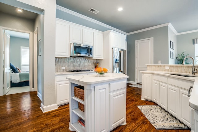 kitchen with stainless steel appliances, white cabinets, a sink, and tasteful backsplash