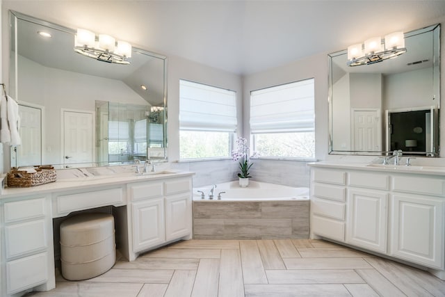 full bath with two vanities, a garden tub, and a notable chandelier