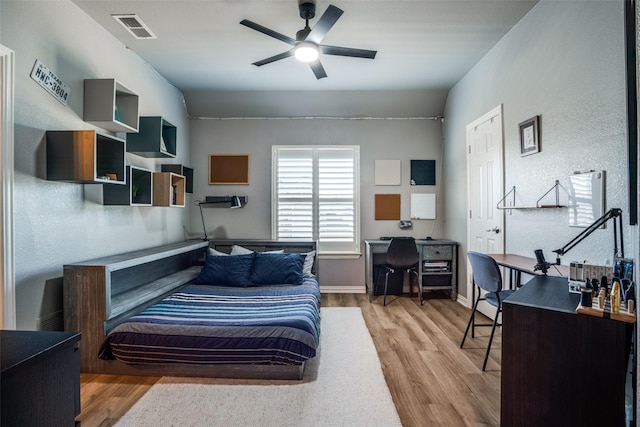 bedroom with wood finished floors, visible vents, and baseboards