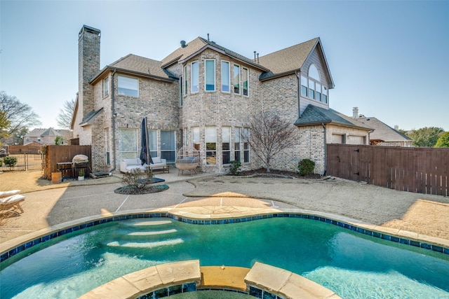 rear view of house with a patio area, brick siding, a chimney, and a fenced backyard