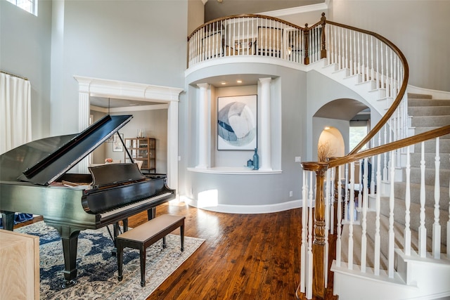 entrance foyer with stairway, wood finished floors, and a towering ceiling