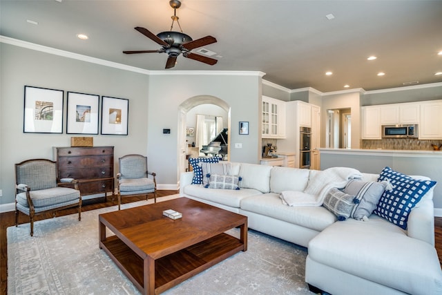 living area with crown molding, arched walkways, and wood finished floors