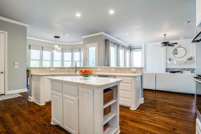 kitchen with visible vents, a ceiling fan, ornamental molding, dark wood-type flooring, and a center island