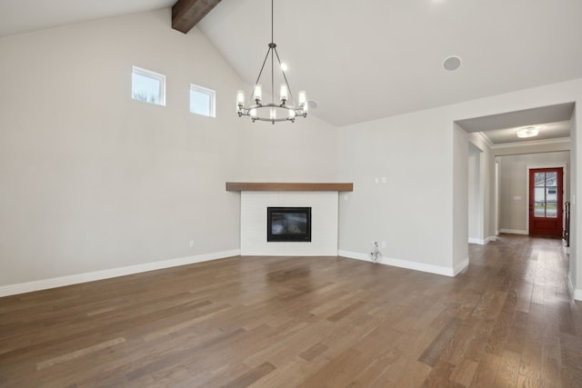 unfurnished living room featuring baseboards, a glass covered fireplace, wood finished floors, beam ceiling, and a notable chandelier