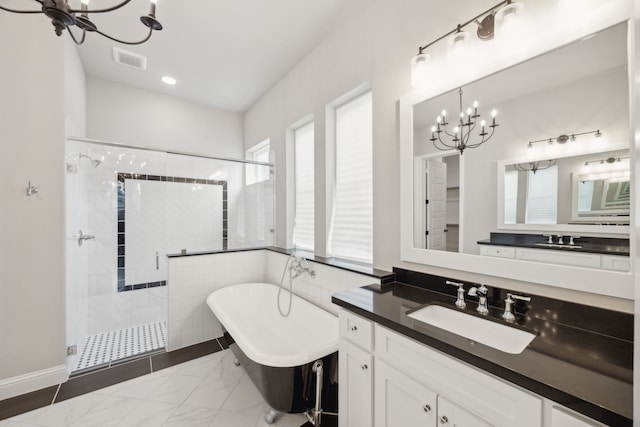 full bathroom featuring marble finish floor, visible vents, a stall shower, a chandelier, and a freestanding tub