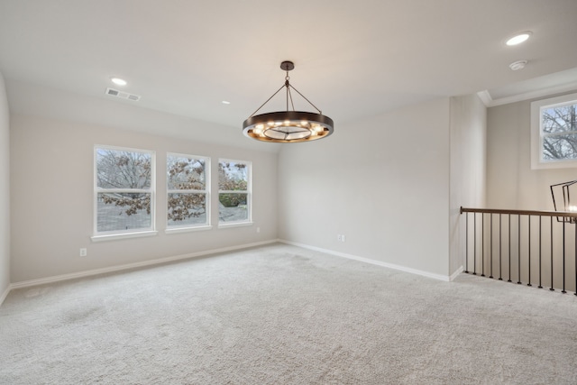 carpeted empty room featuring a healthy amount of sunlight, visible vents, a notable chandelier, and baseboards