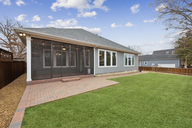 rear view of house featuring a fenced backyard, a shingled roof, a sunroom, a yard, and a patio area