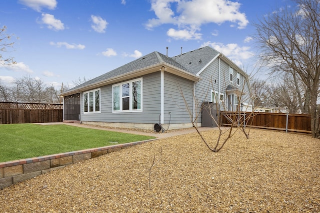 back of house featuring a yard, a shingled roof, and a fenced backyard