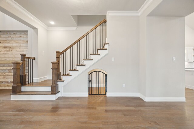 staircase featuring baseboards, wood finished floors, and crown molding