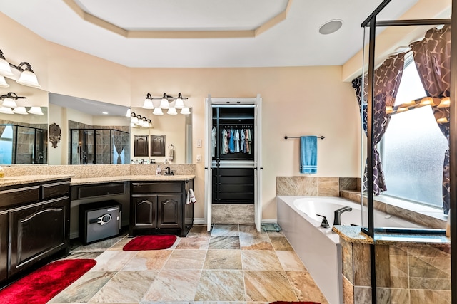 full bathroom featuring a stall shower, a garden tub, vanity, and a tray ceiling