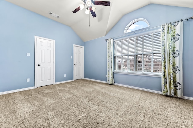 empty room featuring lofted ceiling, carpet floors, a ceiling fan, visible vents, and baseboards