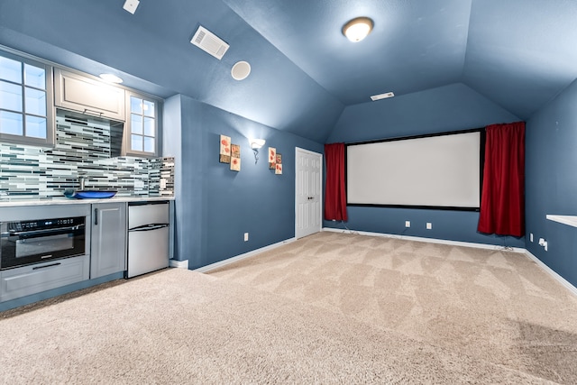 home theater featuring lofted ceiling, baseboards, light carpet, and visible vents