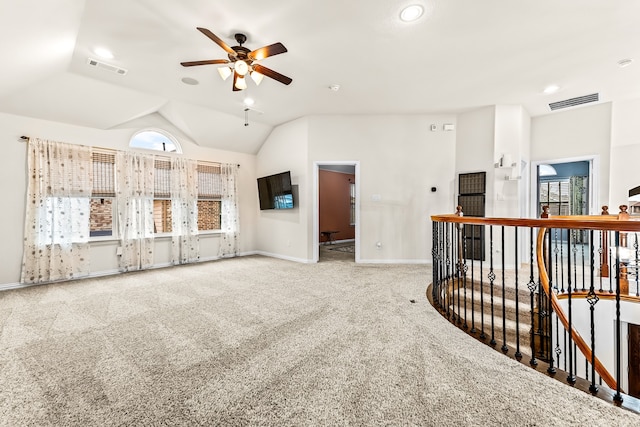 spare room featuring lofted ceiling, carpet flooring, visible vents, baseboards, and a ceiling fan