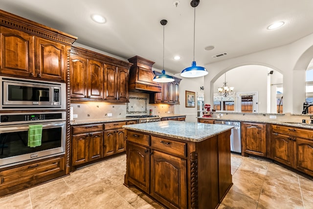 kitchen with arched walkways, decorative backsplash, a kitchen island, appliances with stainless steel finishes, and light stone countertops