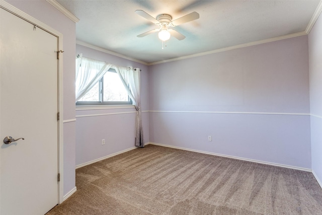 empty room with baseboards, carpet, a ceiling fan, and crown molding