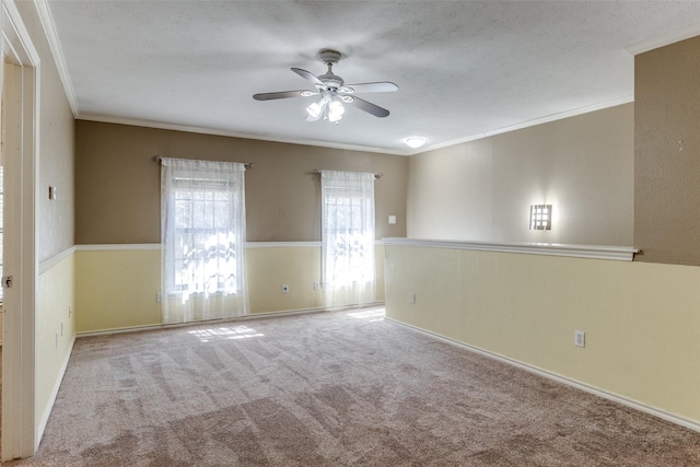 carpeted spare room with ornamental molding, a ceiling fan, and baseboards