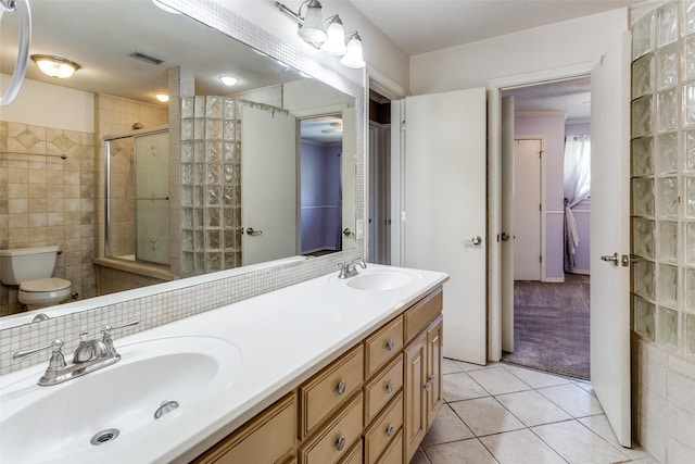 full bath with toilet, tile patterned flooring, a sink, and tiled shower