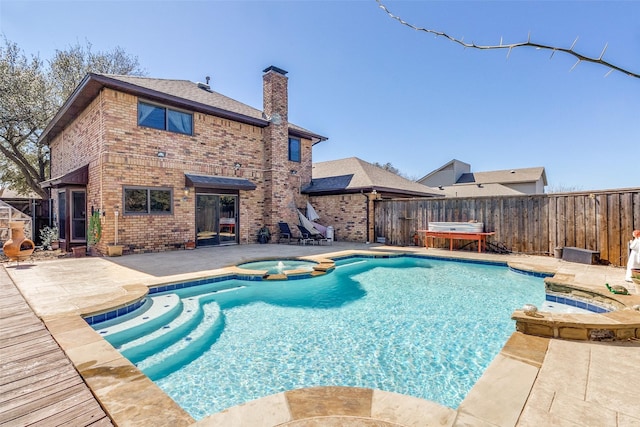 view of pool featuring a fenced backyard, a pool with connected hot tub, and a patio