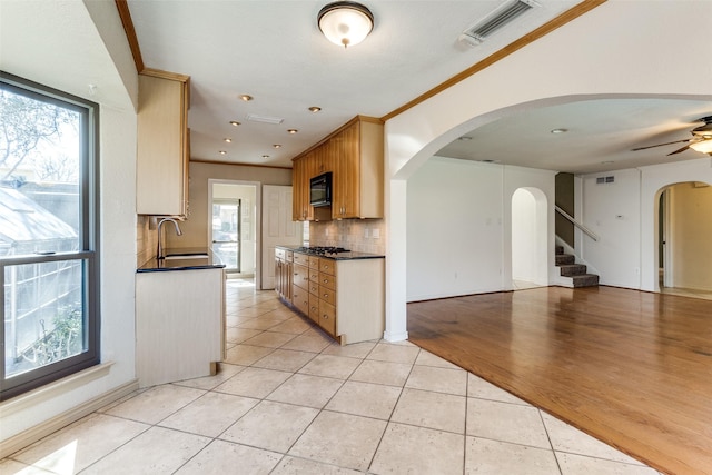 kitchen featuring light tile patterned floors, visible vents, dark countertops, black microwave, and a sink