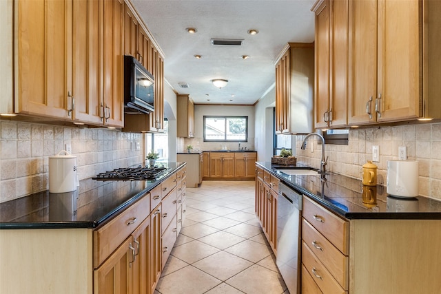 kitchen with stainless steel appliances, tasteful backsplash, visible vents, light tile patterned flooring, and a sink