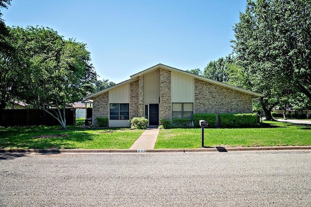 mid-century home with a front yard and brick siding