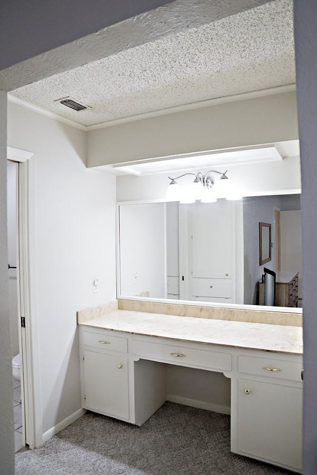 bathroom featuring baseboards, visible vents, a textured ceiling, and vanity