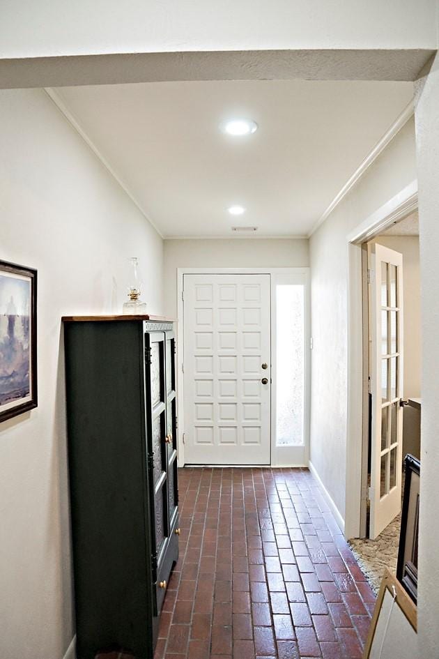 entryway with baseboards, recessed lighting, brick floor, and crown molding